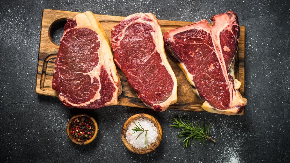 Tabla de cortar con tres filetes de ISA Foods y pequeños recipientes con condimentos